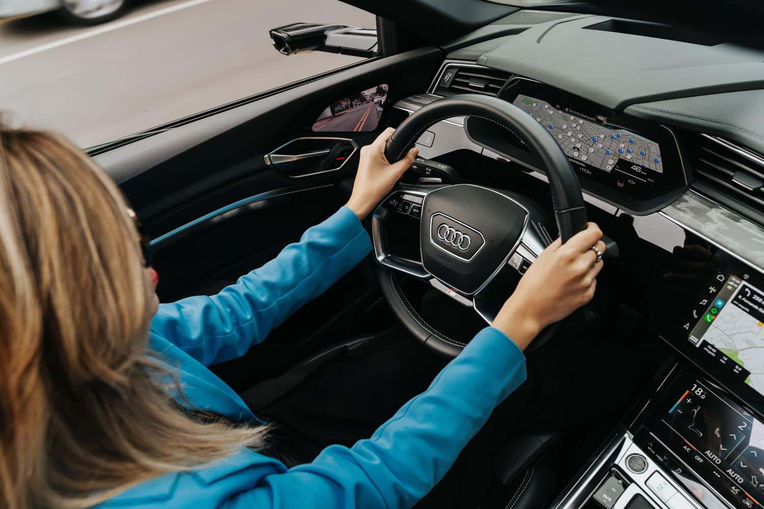 Perspectiva del conductor en un Audi moderno, enfocada en el volante y la experiencia de conducción digital.