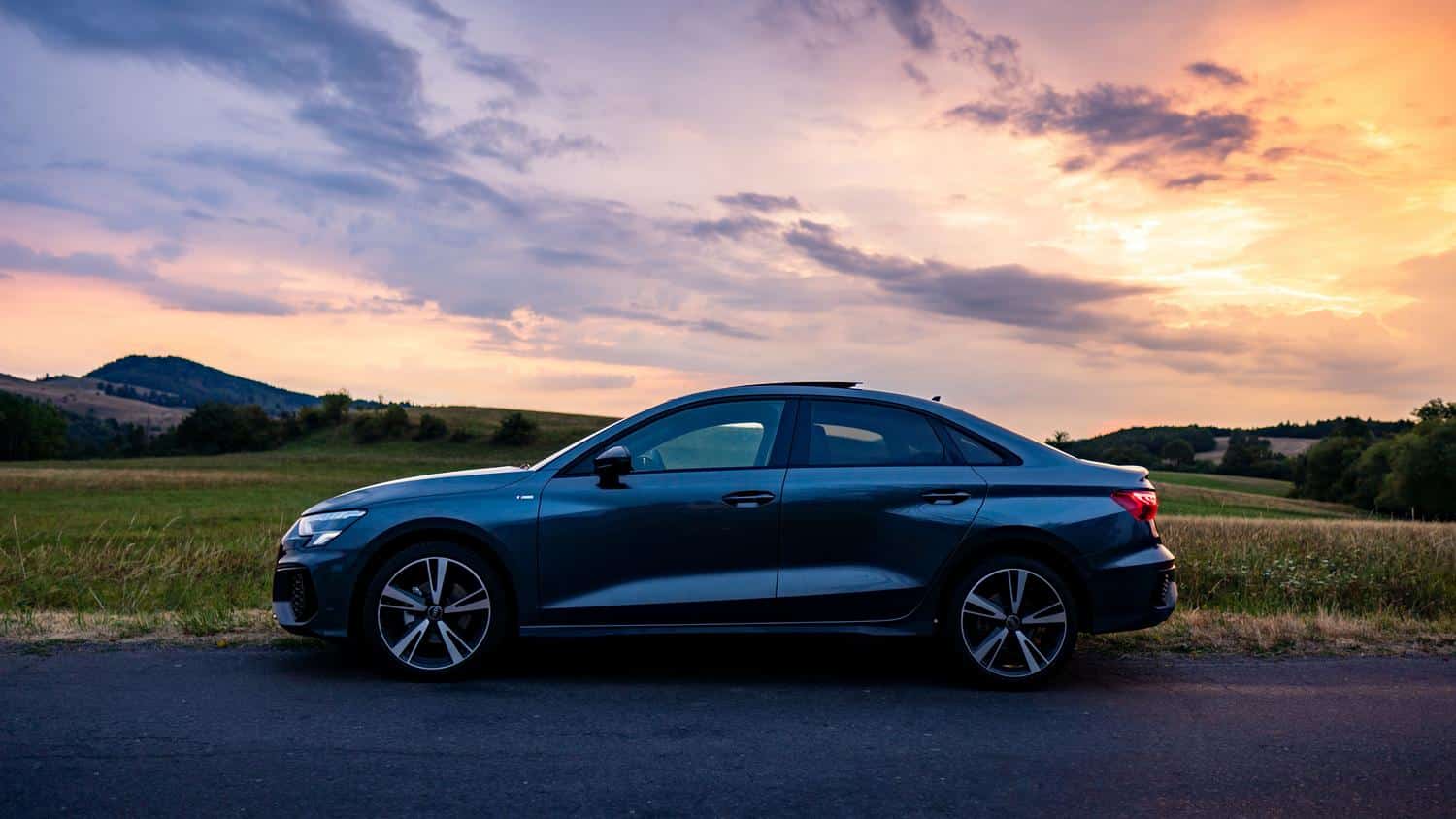 Vista frontal y lateral de un Audi A3 Sedan negro bajo la luz del atardecer, destacando su diseño aerodinámico y la parrilla Singleframe.