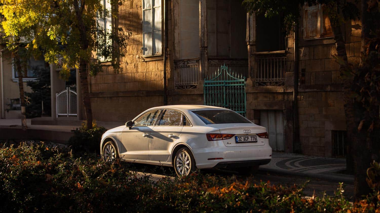Perfil lateral de un Audi A3 Sedan blanco estacionado en una calle urbana, resaltando su silueta elegante y sofisticada.