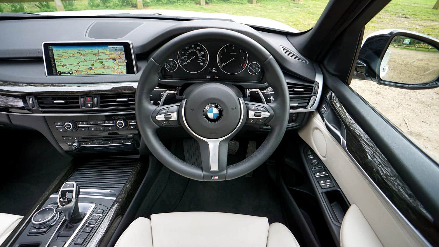 Interior lujoso de un BMW X5 con volante M-Sport y pantalla de navegación, mostrando la tecnología y el confort interior.