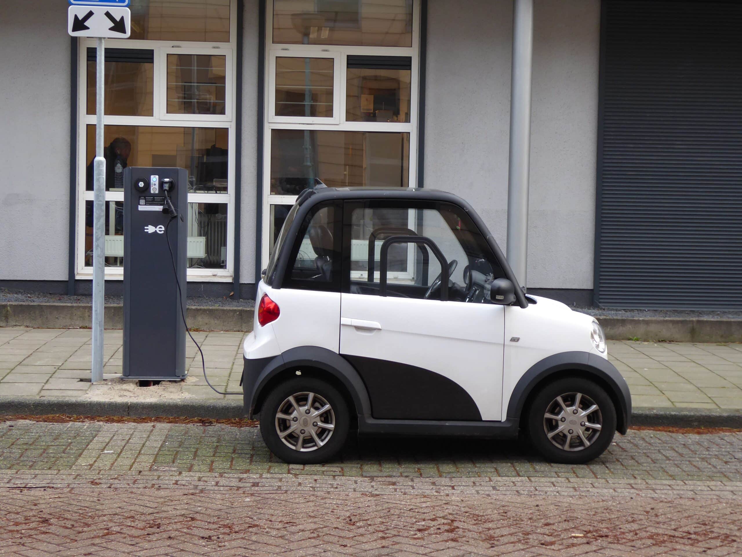 Coche eléctrico compacto cargando en una estación de carga pública urbana.