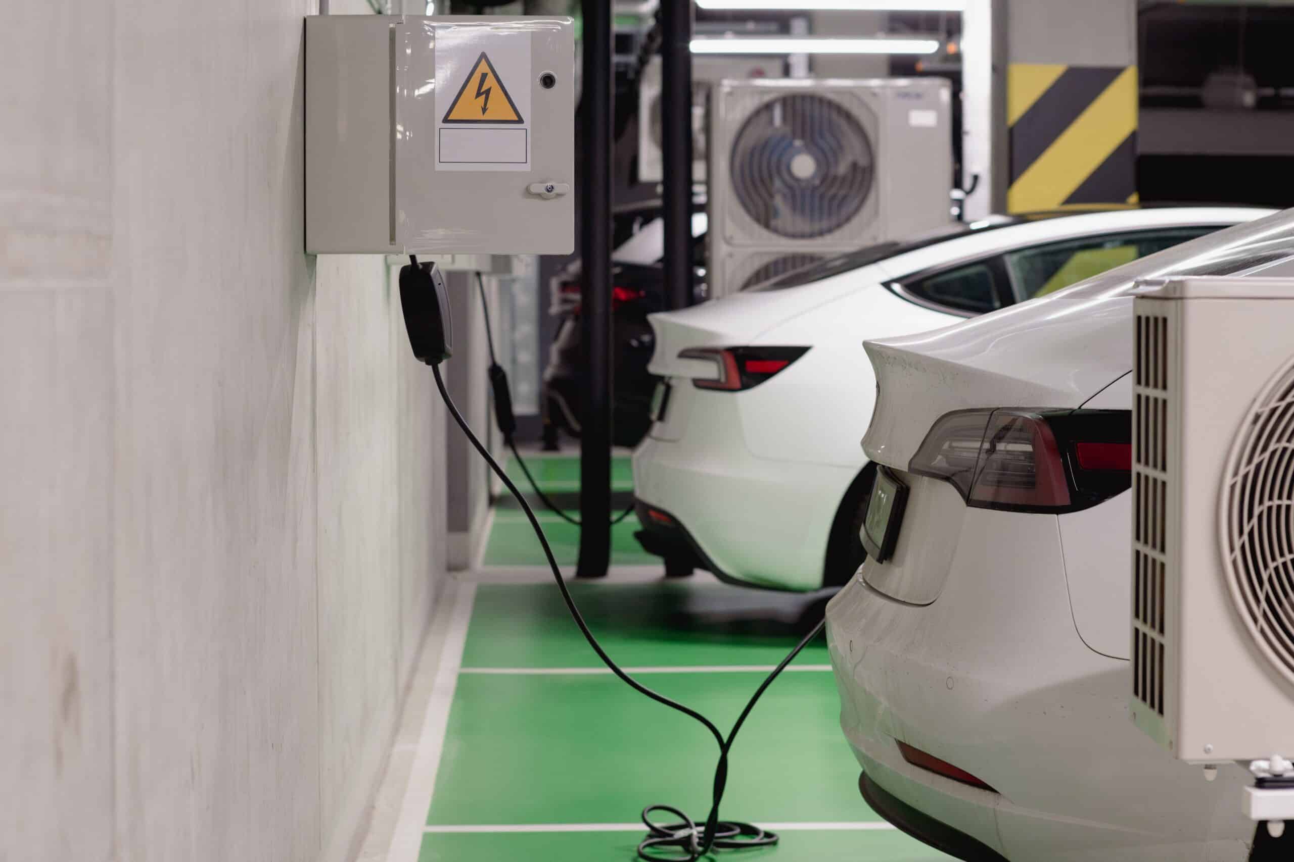 Coches eléctricos cargando en un parking subterráneo moderno, ejemplificando la infraestructura de carga robusta.
