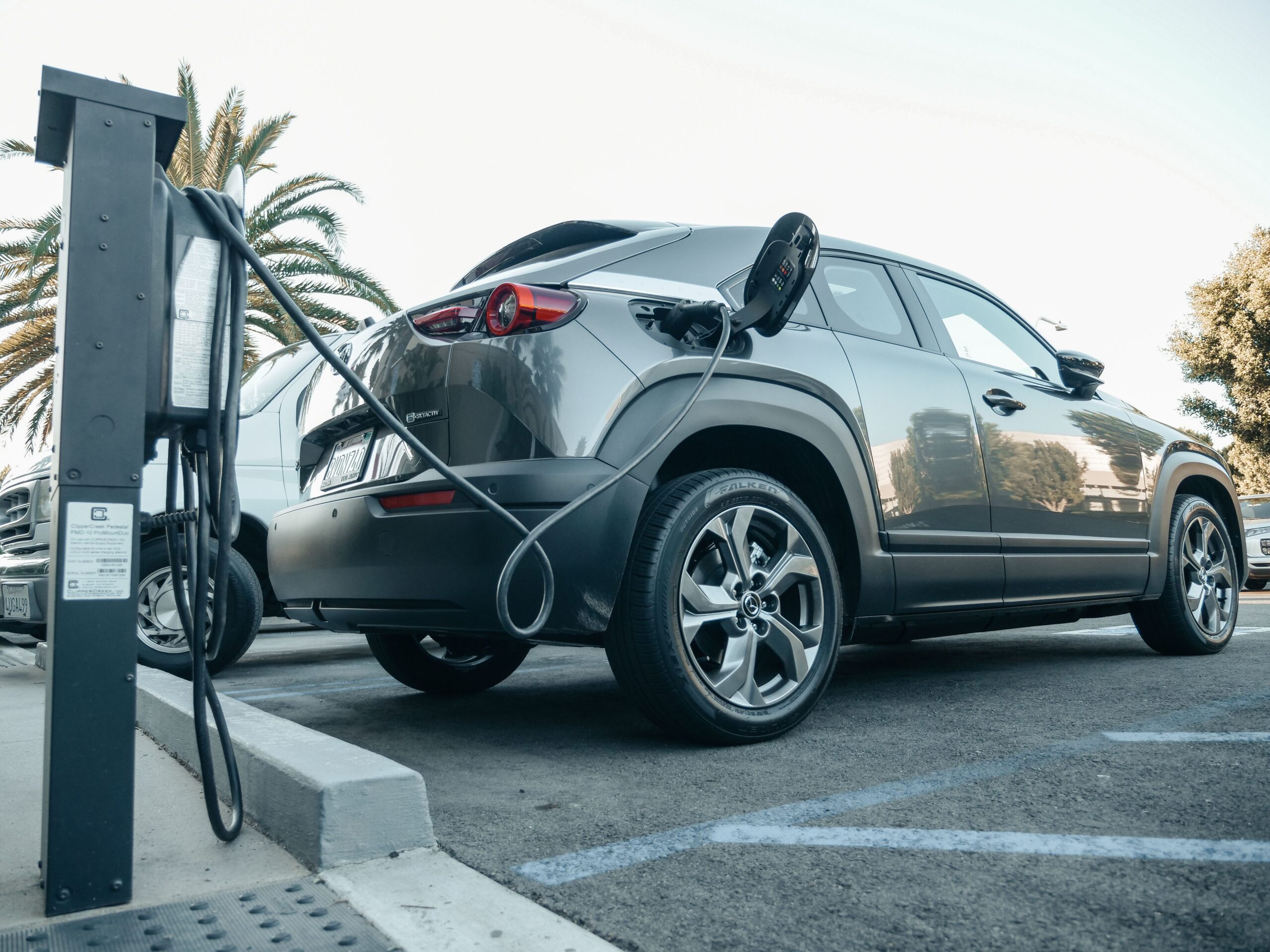 Modern electric SUV charging at an outdoor station in daylight.