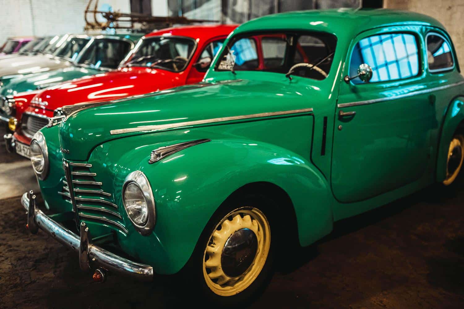 Colección de coches vintage de colores brillantes alineados en un museo, una imagen atractiva y visual para visitas familiares.