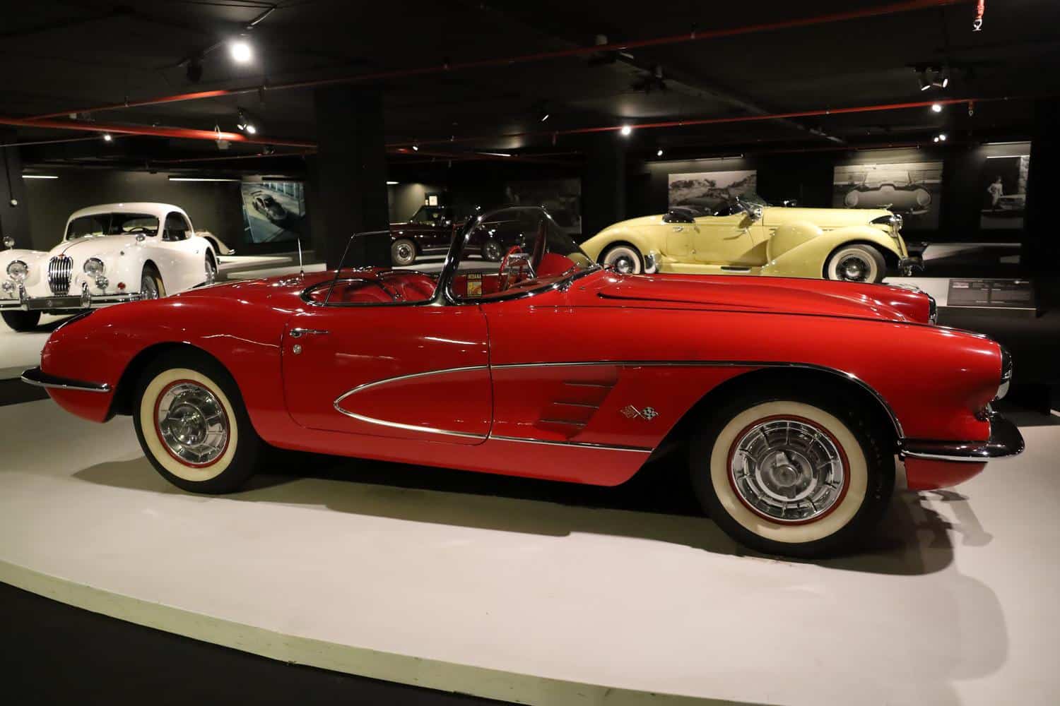 Chevrolet Corvette rojo clásico en exhibición, resaltando el diseño aerodinámico y los detalles cromados de los coches antiguos.
