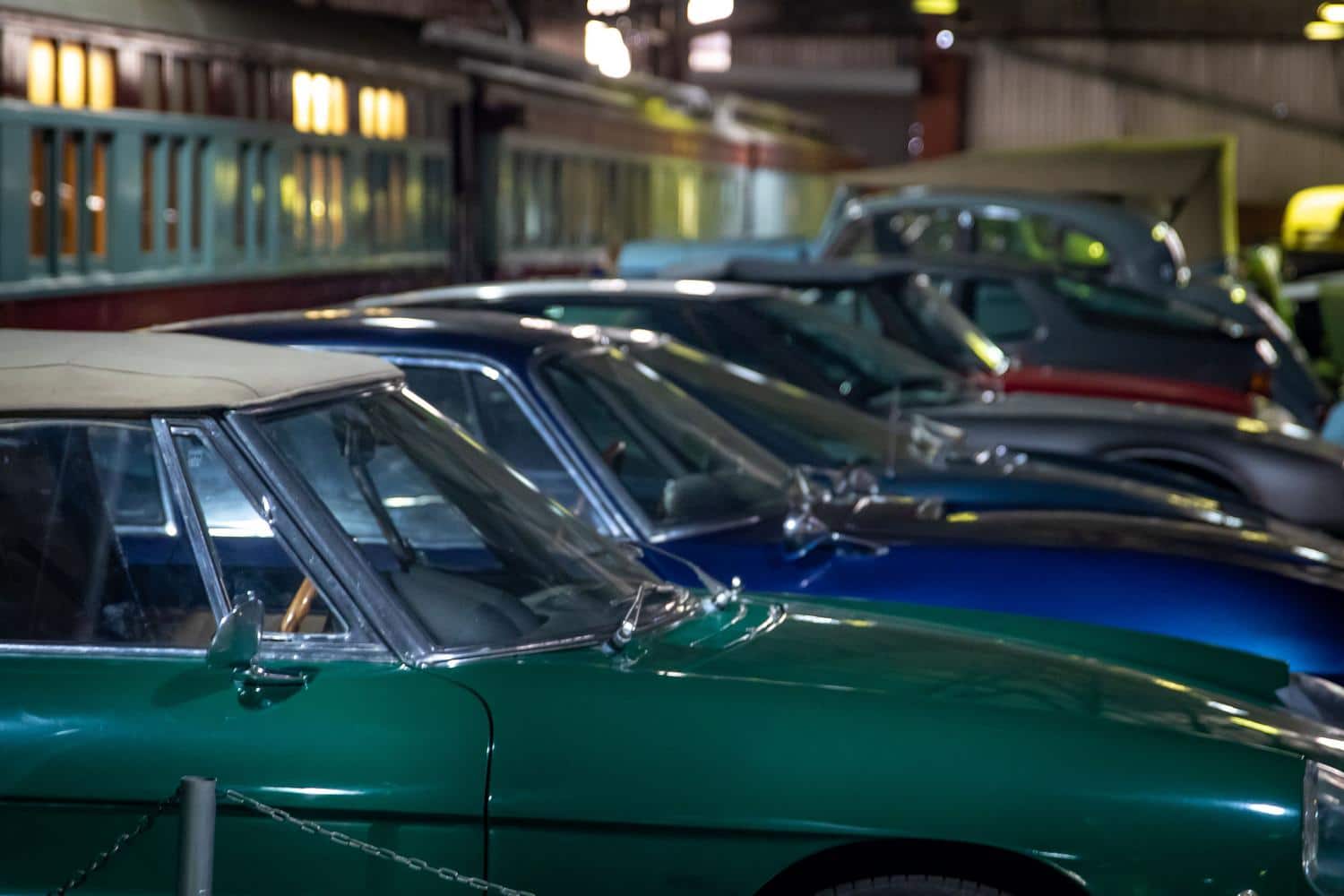 Fila de coches clásicos vintage en un museo de transporte, mostrando una colección variada de vehículos históricos.