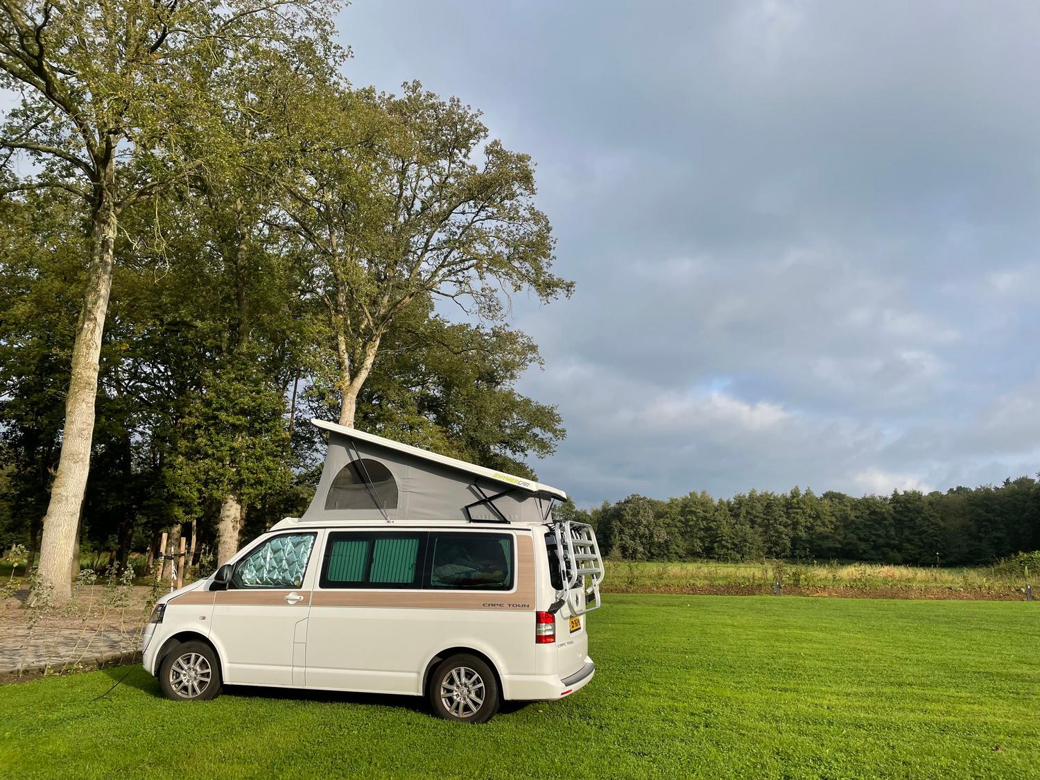 Camper van estacionada en un prado verde, simbolizando la conexión con la naturaleza y la versatilidad del vehículo.