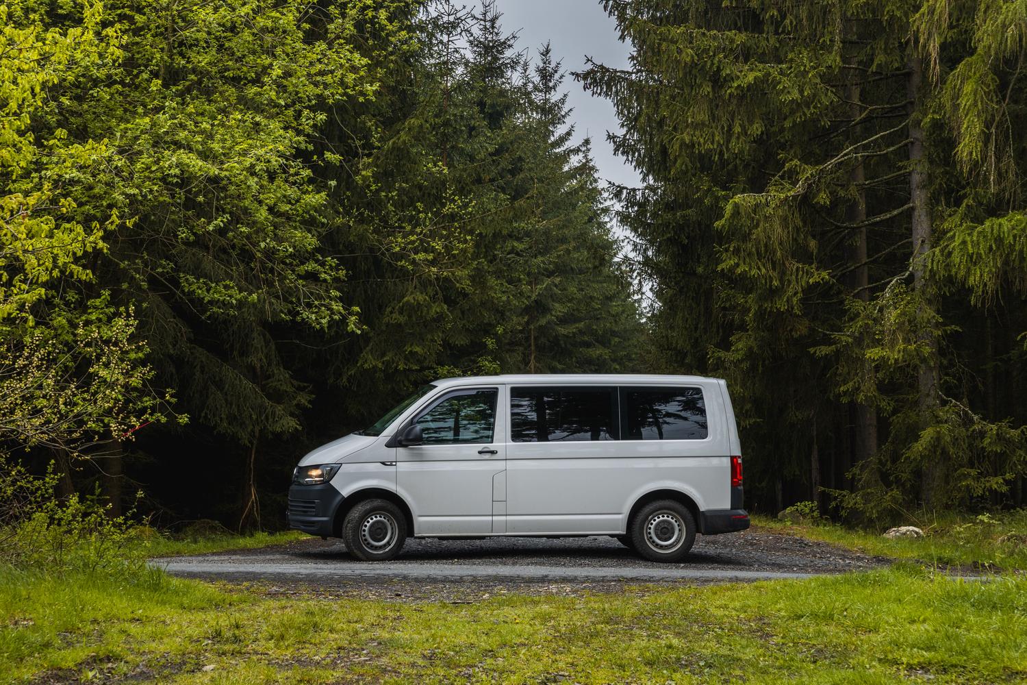 Furgoneta camper moderna estacionada en un bosque tranquilo, representando el estilo de vida nómada y la libertad de viajar.