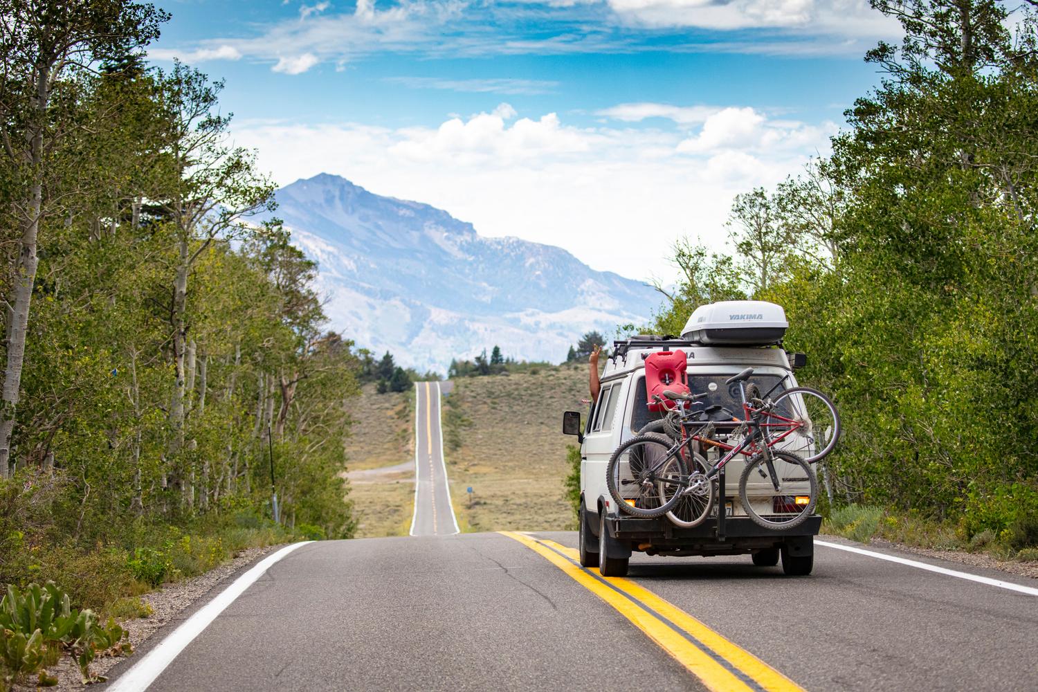 Camper van recorriendo un impresionante paisaje montañoso, ideal para ilustrar las rutas de larga distancia y la aventura.