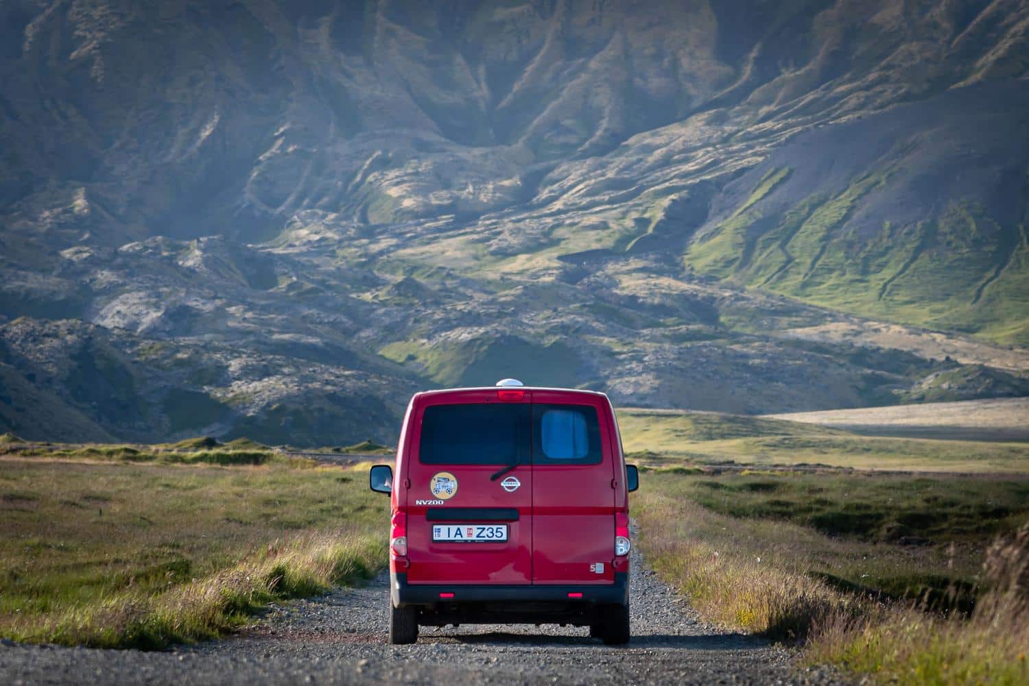 Camper roja recorriendo los paisajes naturales de Islandia durante el verano, ideal para rutas de expedición.