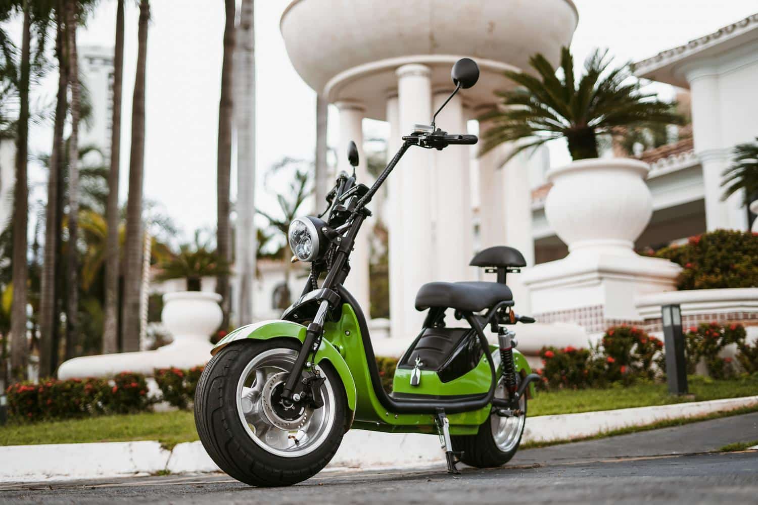 Ciclomotor eléctrico de color verde aparcado en una zona urbana, representando la movilidad sostenible.