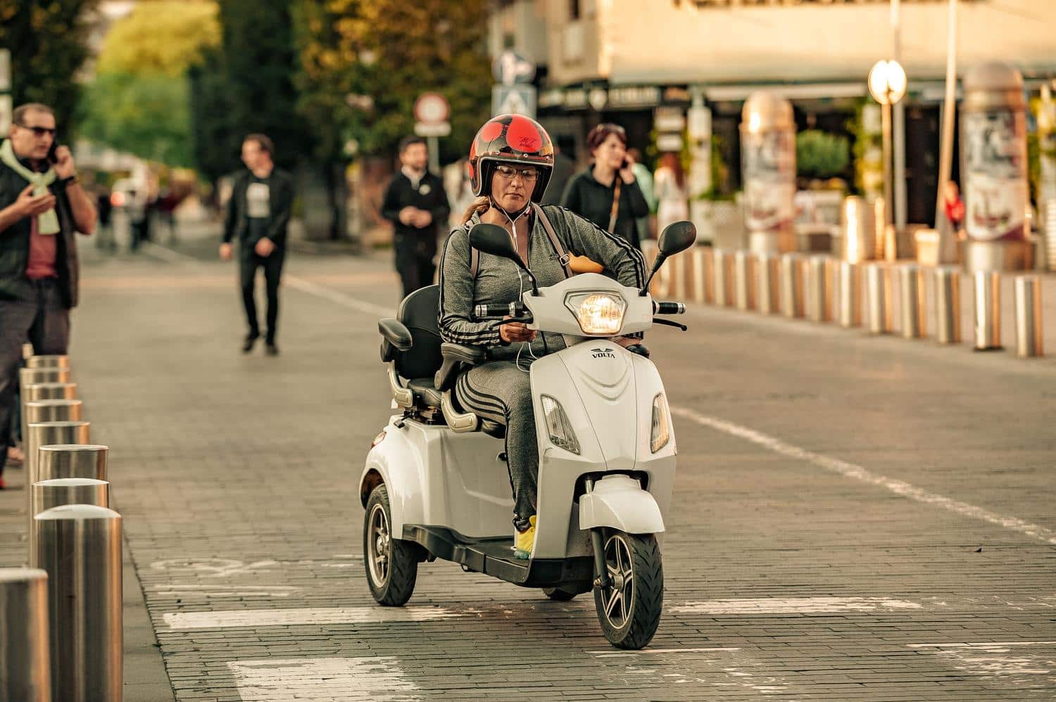 Mujer utilizando su smartphone sentada en un ciclomotor eléctrico, ilustrando la practicidad del vehículo en el día a día.