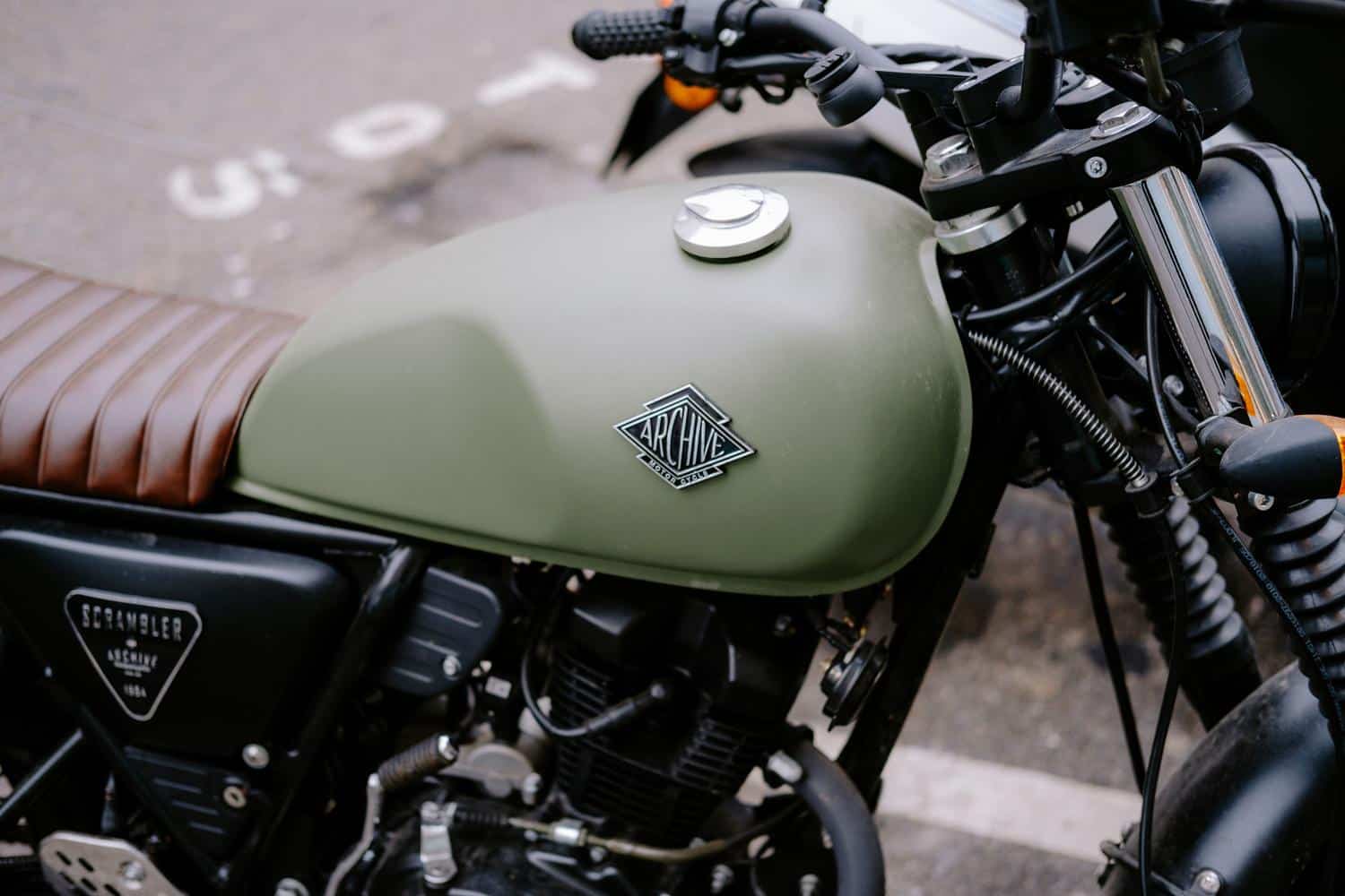 Primer plano del tanque de combustible verde oliva de una moto estilo scrambler.