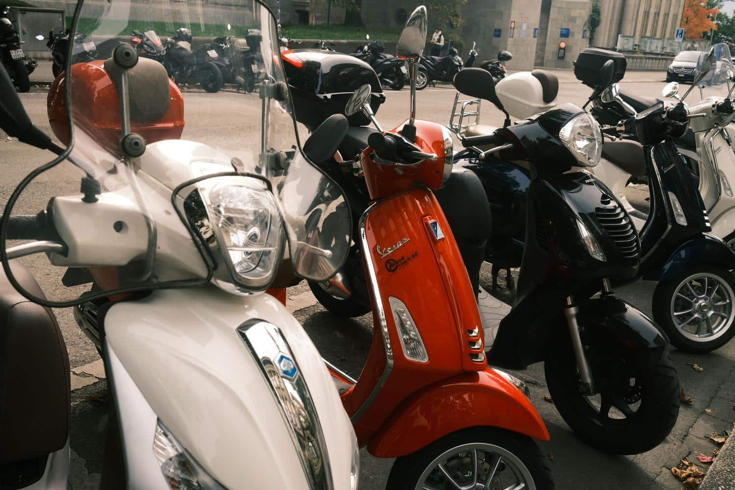Varias scooters urbanas de colores vivos aparcadas en la ciudad.