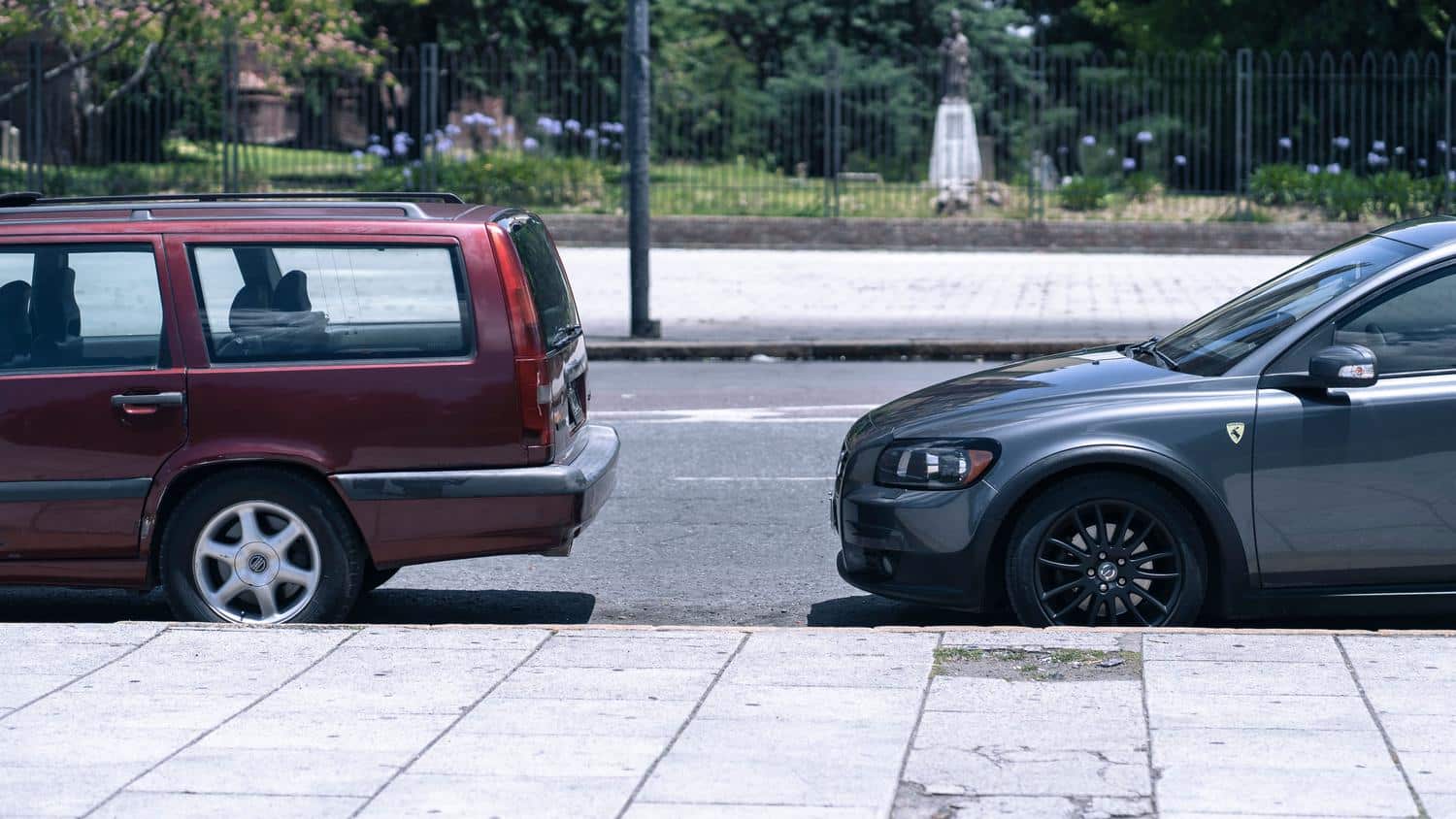 Dos coches aparcados correctamente en paralelo en una calle soleada de la ciudad.