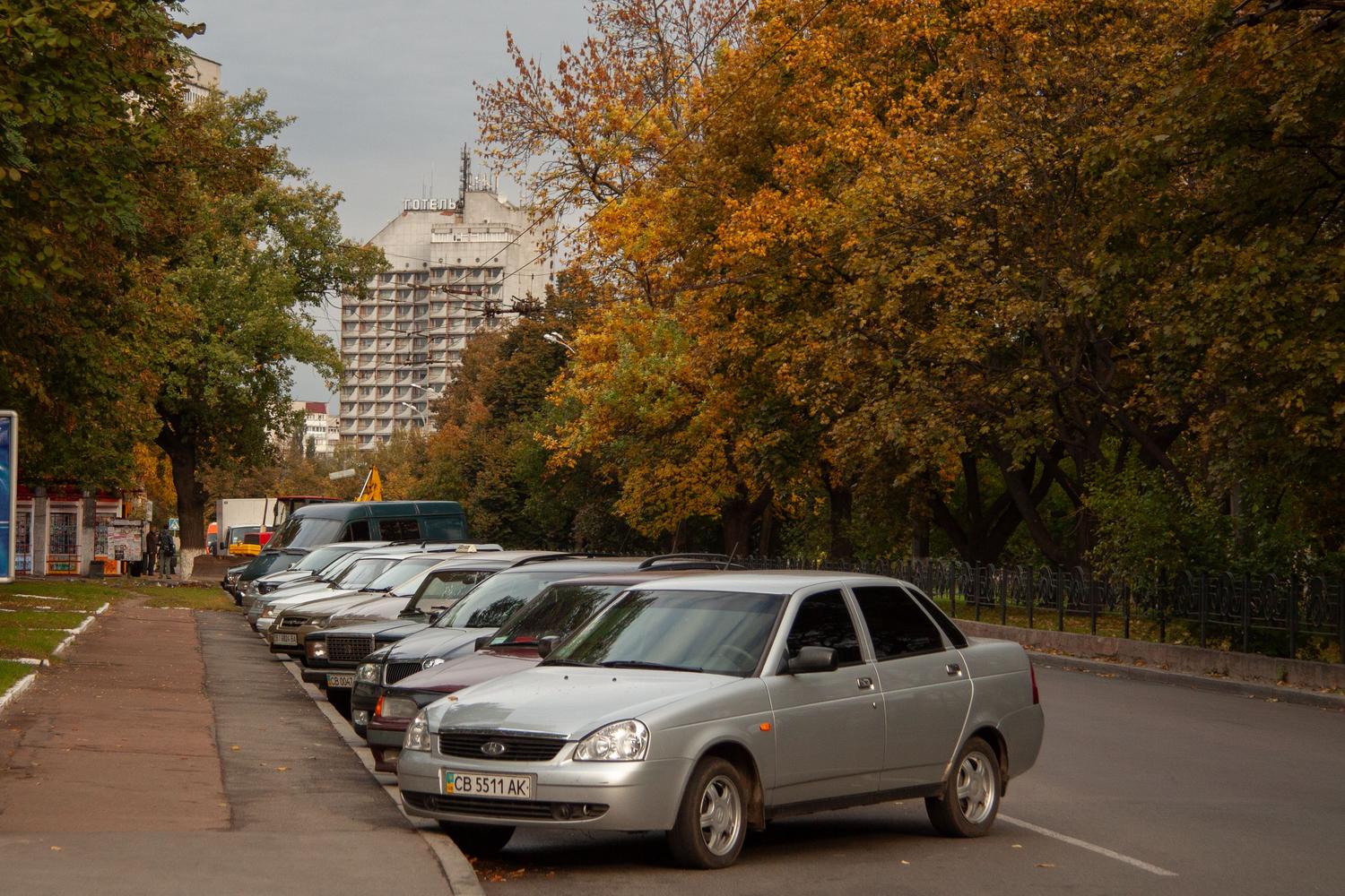 Coches aparcados en paralelo en una calle residencial tranquila durante el otoño.