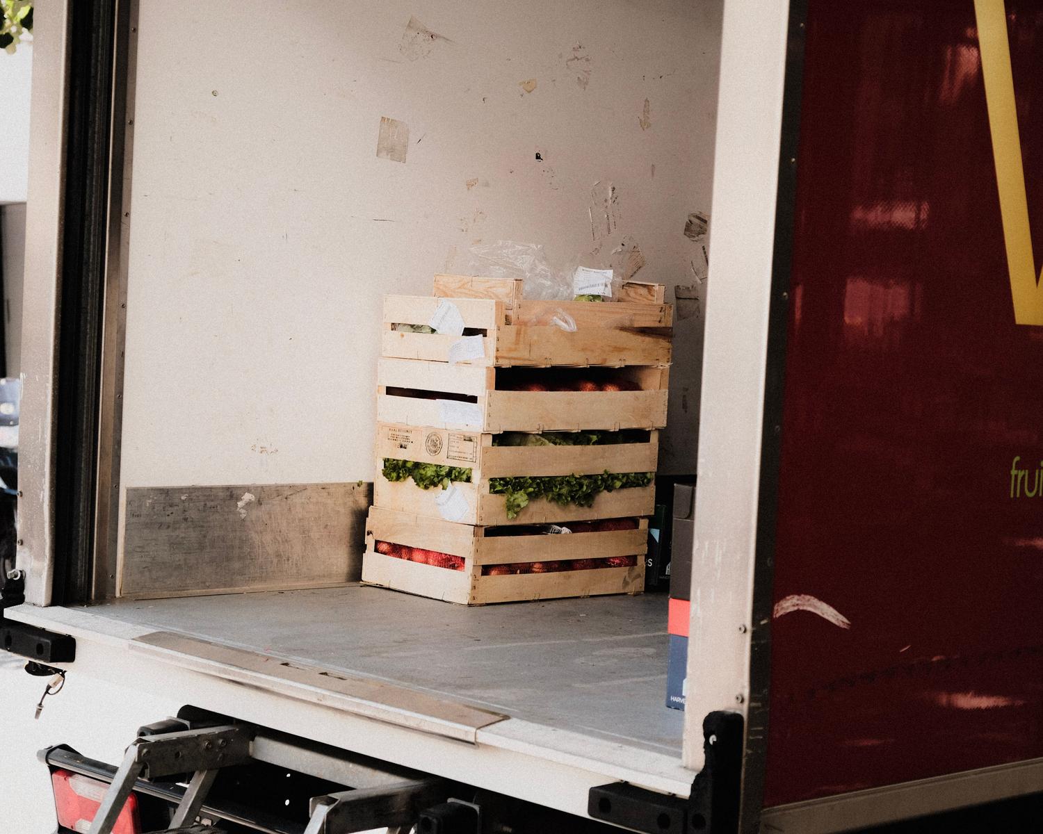 Interior de un camión de reparto con cajas de frutas y verduras frescas, ejemplificando la tipología de carga perecedera