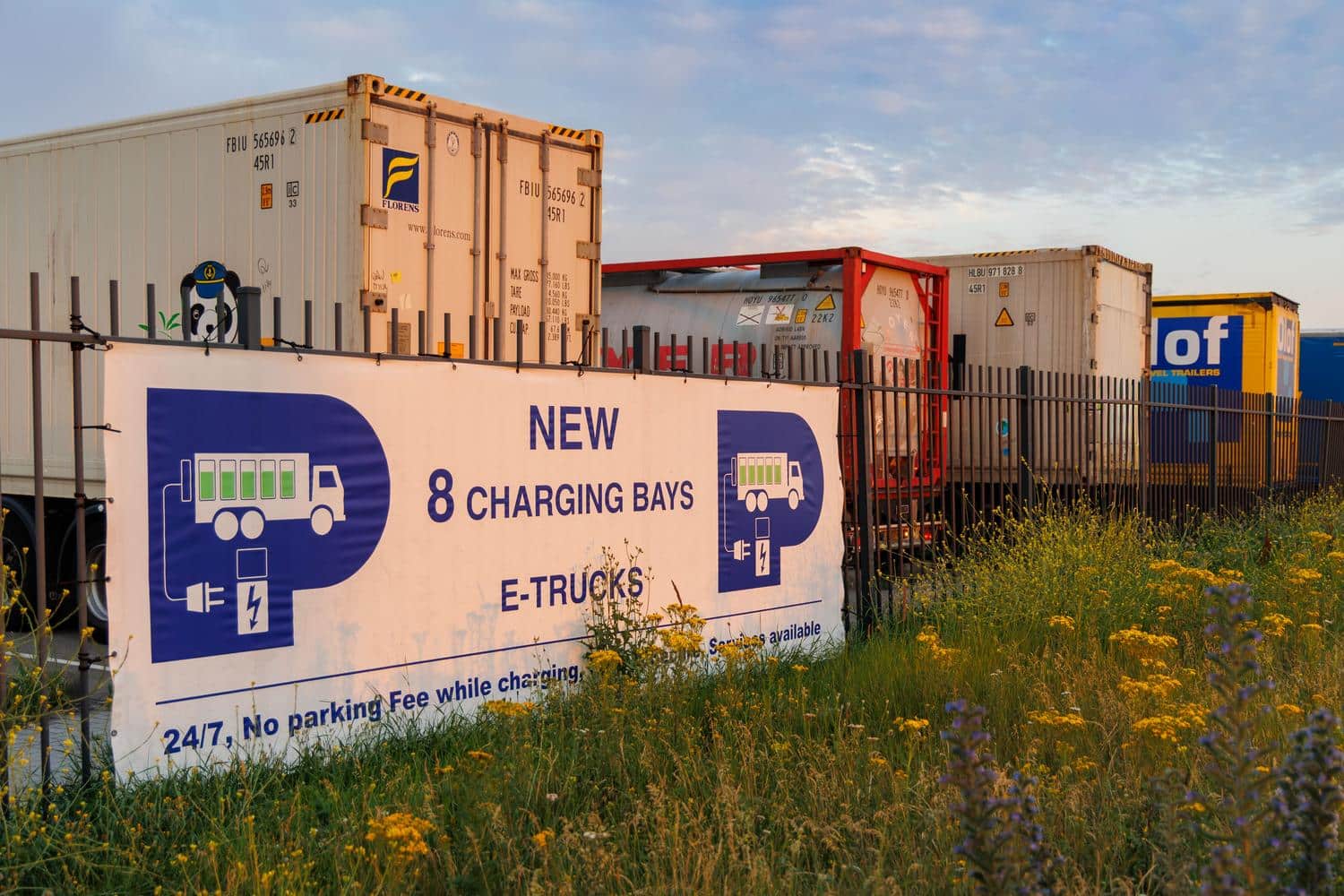 Cartel de bahías de carga para camiones eléctricos en un entorno logístico, ilustrando la sostenibilidad y electrificación de flotas