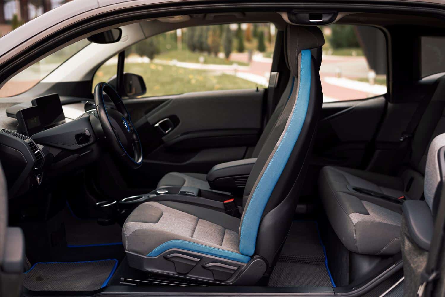 Detalle del interior de un coche eléctrico moderno con acabados tecnológicos y asientos deportivos, representando la experiencia de conducción.