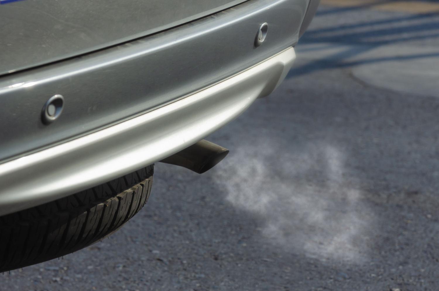 Primer plano de un tubo de escape de coche emitiendo humos, ilustrando las emisiones contaminantes que detectan los radares de gases.
